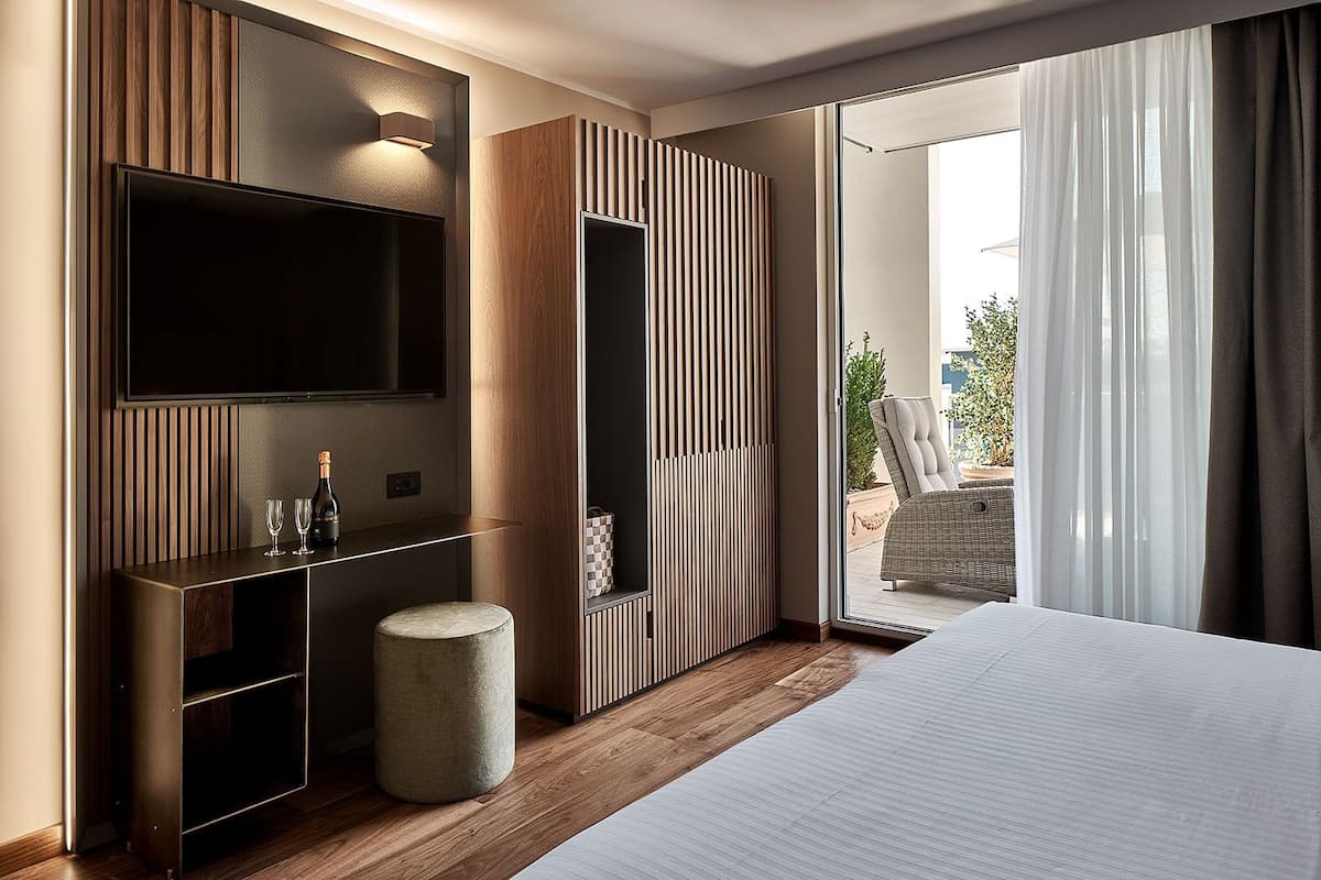 Habitación de hotel moderna con una cama grande, televisión, minibar y vistas al exterior.