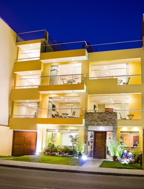 A multi-story hotel with balconies, a stone facade, and a well-lit entrance. - Alwa Premium Hotel Boutique (Arequipa)