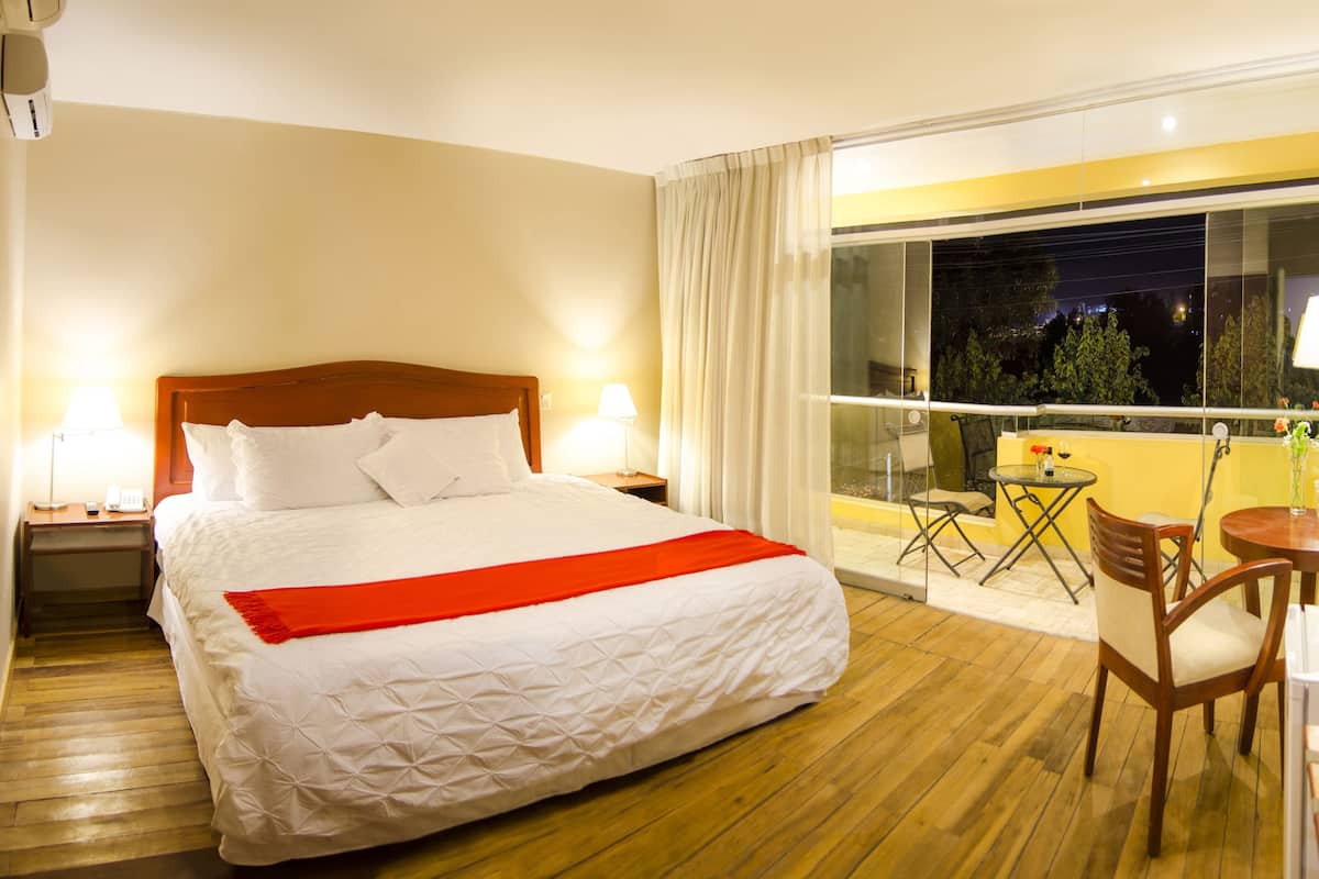 Hotelkamer met een groot bed, een balkon met een tafel en stoelen, en uitzicht op de nachthemel.