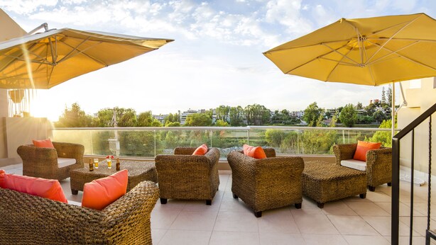 A balcony with wicker furniture and yellow umbrellas, overlooking a cityscape. - Alwa Premium Hotel Boutique (Arequipa)