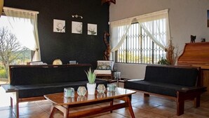 A living room with two sofas, a coffee table, and a piano. - Elephant's Nest Guest House (Graskop)