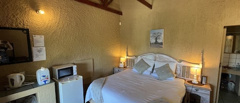 A bedroom with a bed, bedside tables, a desk, a mirror, and a ceiling fan.