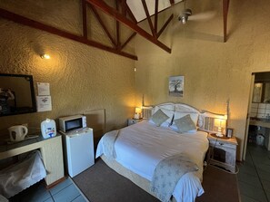 A bedroom with a bed, bedside tables, a desk, a mirror, and a ceiling fan. - Elephant's Nest Guest House (Graskop)