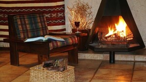 A cozy room with a wooden bench, a fireplace, and a woven basket on the floor. - Elephant's Nest Guest House (Graskop)