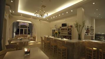A modern kitchen with a bar area, dining space, and a chandelier.