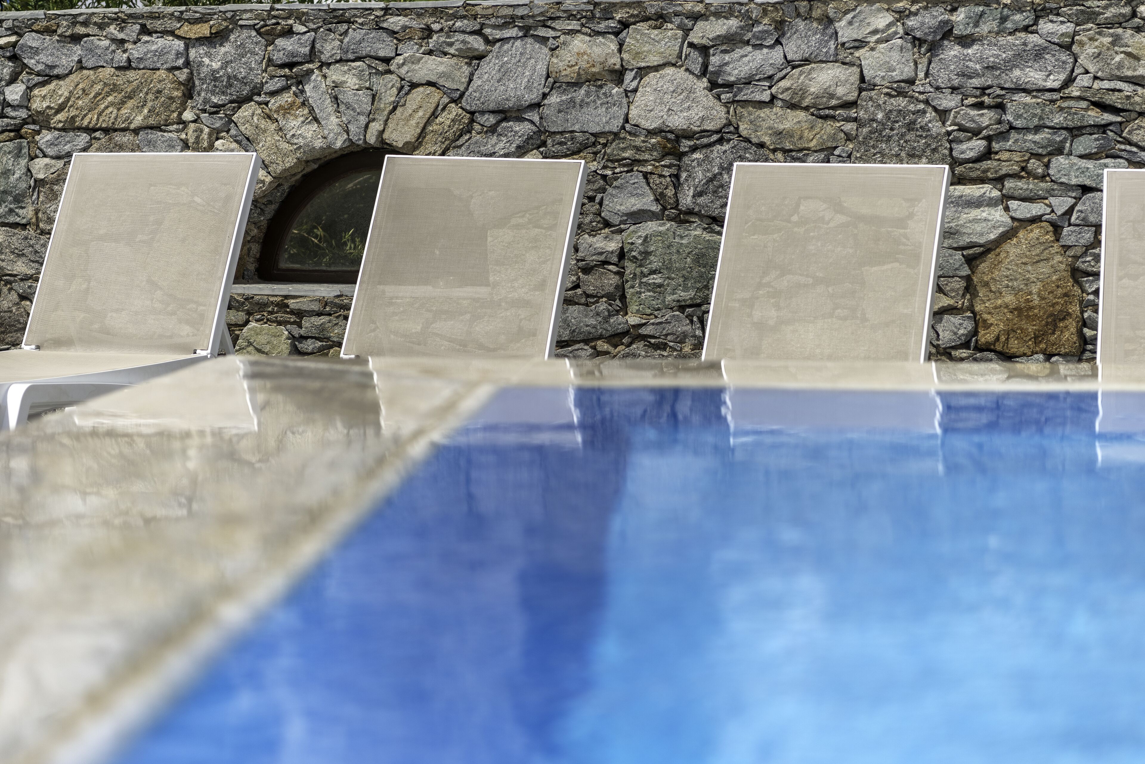 A stone wall with a pool in the foreground.