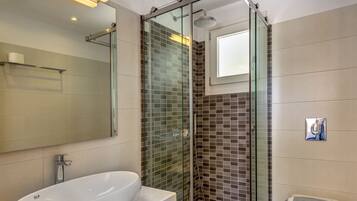 A modern bathroom with a large white bathtub, a glass-enclosed shower, and a white toilet.