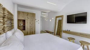 Un dormitorio moderno con una cama grande, cabecera de madera, un televisor y un banco de madera.