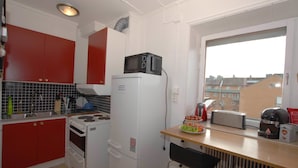 A compact kitchen with red cabinets, a white refrigerator, a microwave, a toaster, and a sink. - Avesta Stadshotell (Avesta)