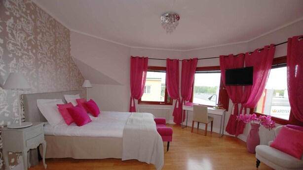 A bedroom with a bed, a desk, a chair, a TV, and a window with curtains. - Avesta Stadshotell (Avesta)