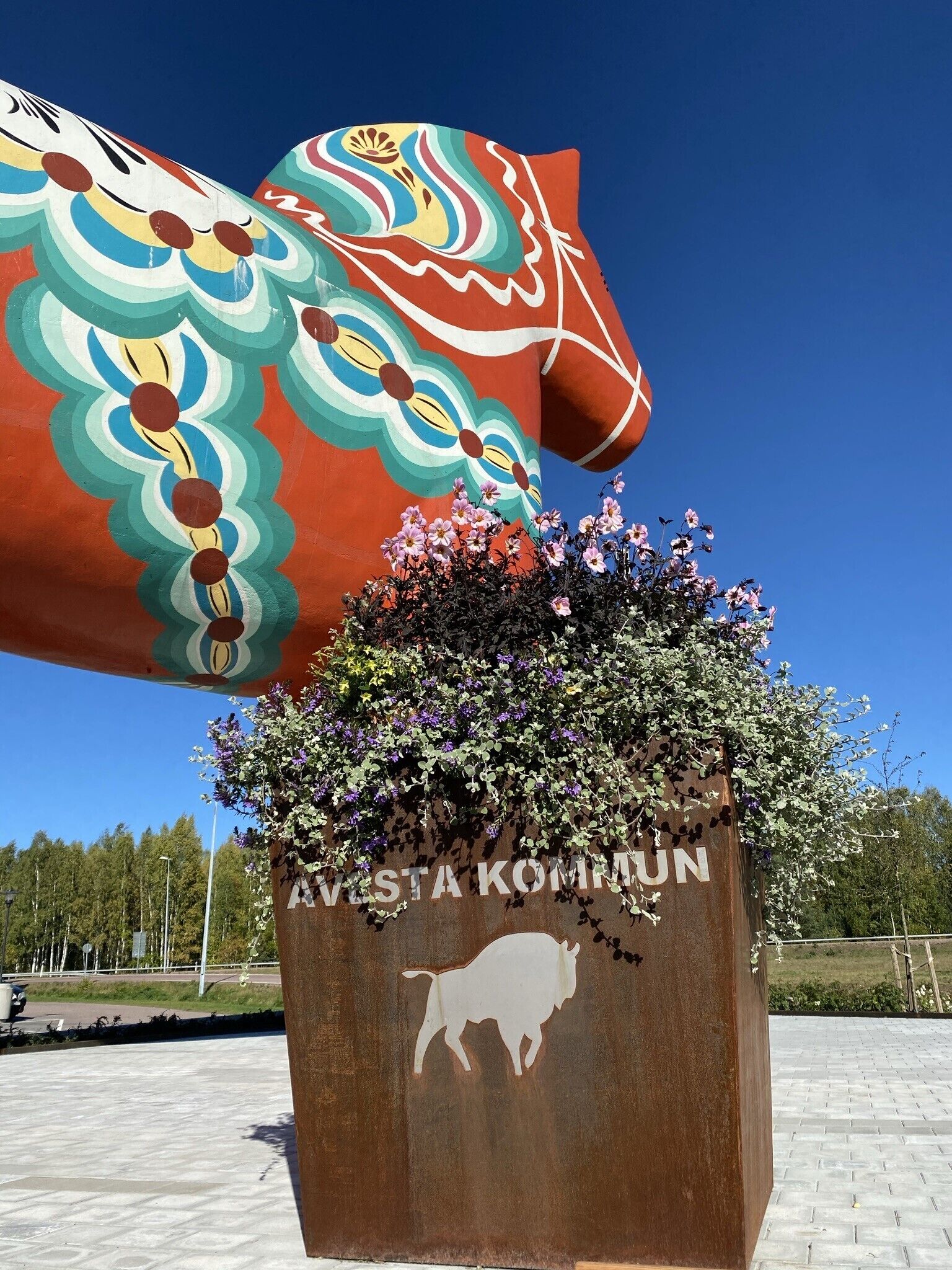Una escultura colorida de cabeza de toro con una jardinera floral debajo.