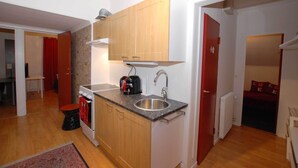 A compact kitchen with wooden cabinets, a stainless steel sink, and a built-in oven. - Avesta Stadshotell (Avesta)