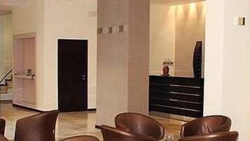 A hotel lobby with leather chairs, a reception desk, and a staircase.