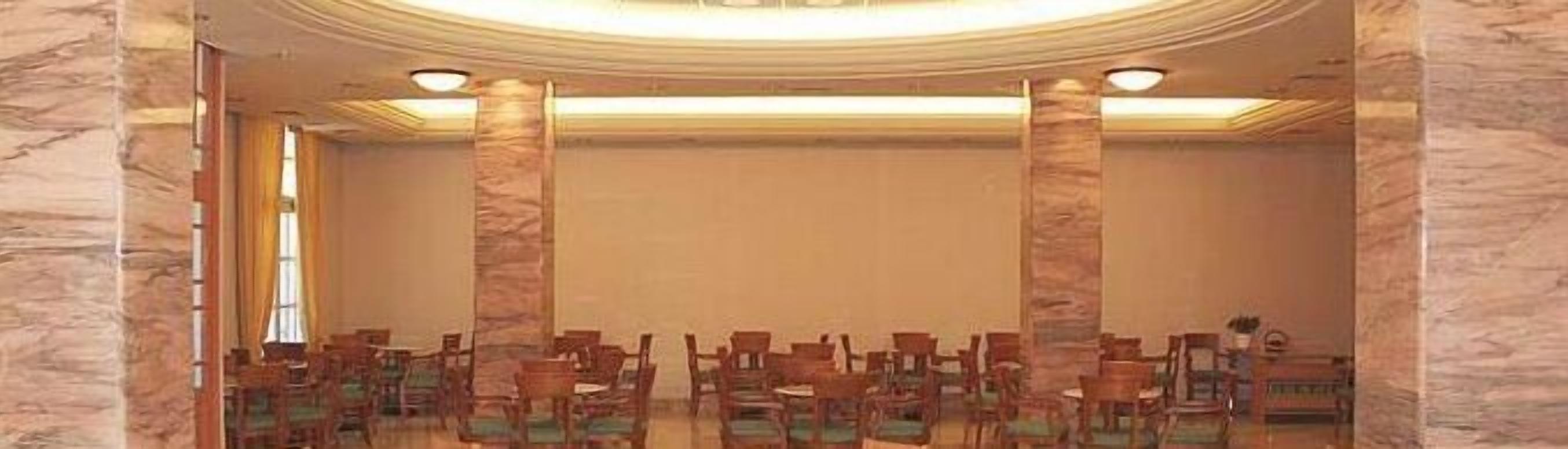 Ein Konferenzraum mit hoher Decke, Marmorsäulen und Reihen von Stühlen.