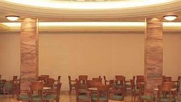 Ein Konferenzraum mit hoher Decke, Marmorsäulen und Reihen von Stühlen.