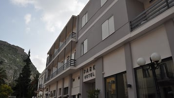 A multi-story hotel with balconies, a sign reading "PARK HOTEL," and a mountainous backdrop.
