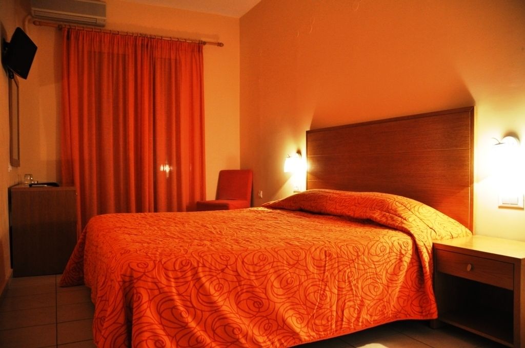 Une chambre d’hôtel avec un lit, une table de chevet, une chaise et un téléviseur fixé au mur.