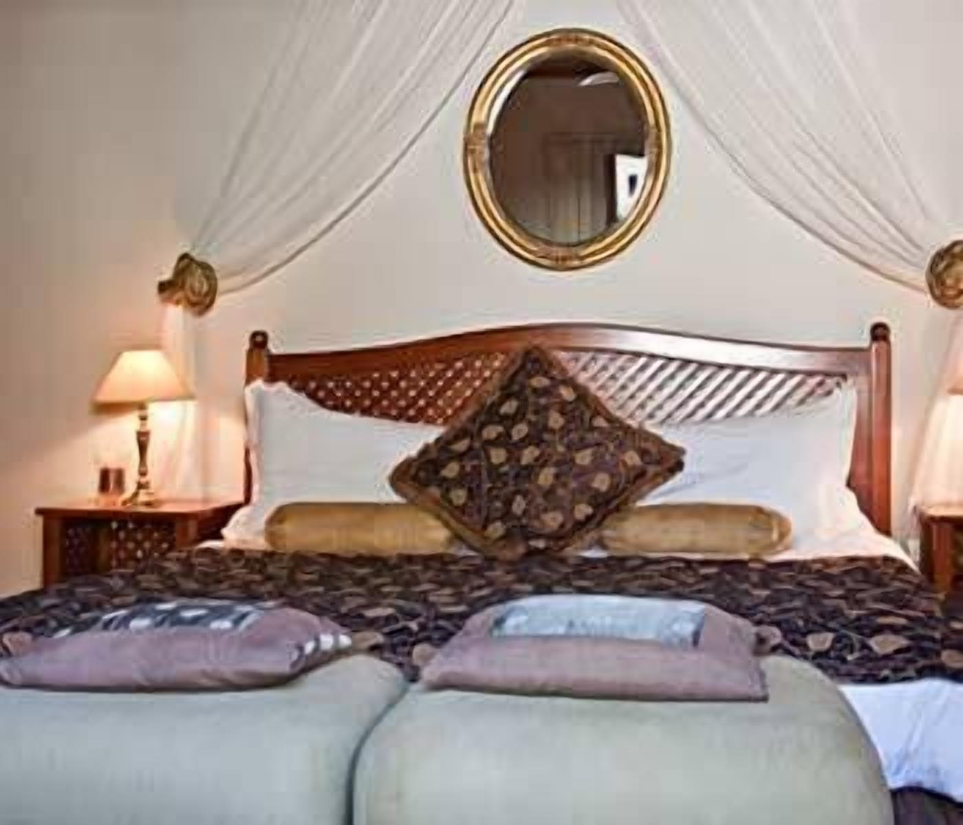 Ein Bett mit Baldachin, ein runder Spiegel und ein Kissen mit Muster.