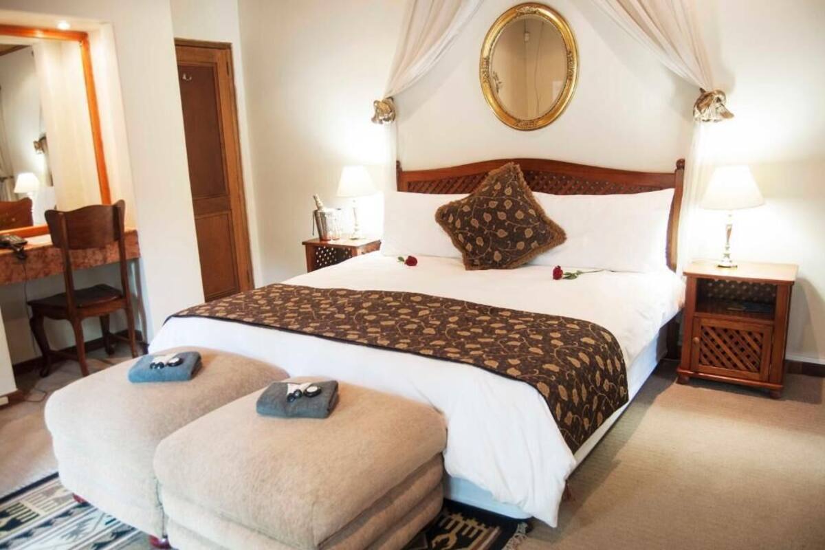 A neatly arranged bedroom with a bed, bedside tables, a mirror, and a chair.