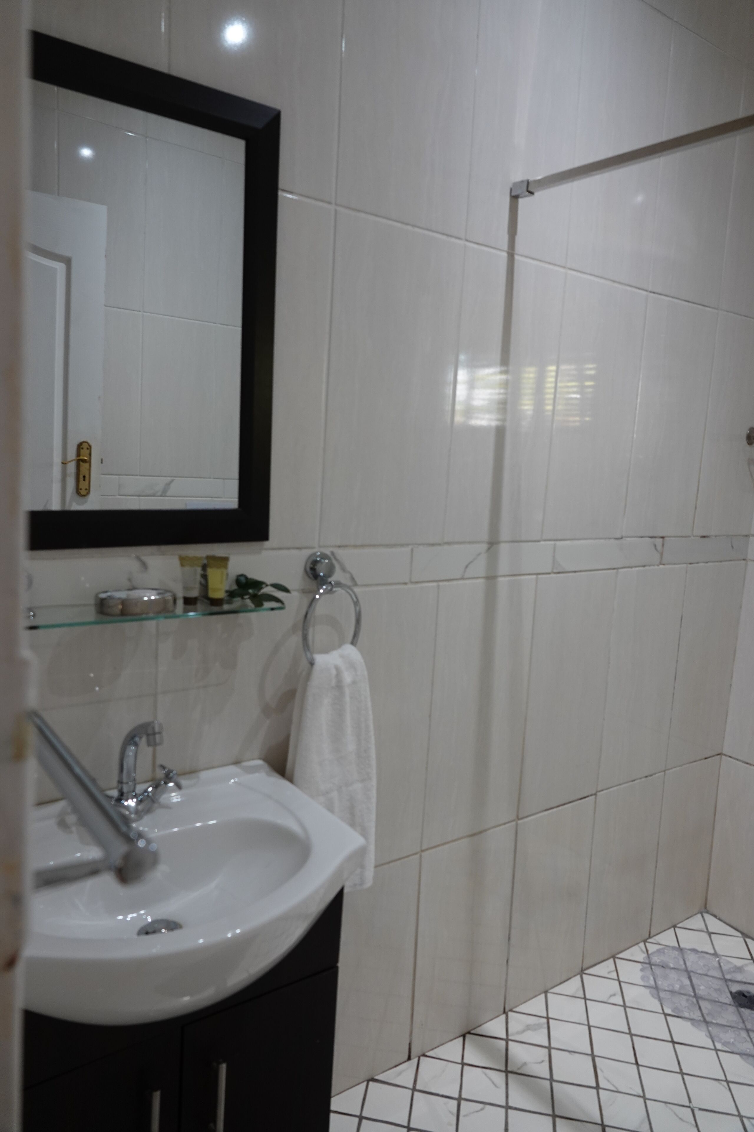 Un baño con lavamanos blanco, espejo y ducha.