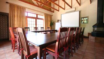 Un salón de conferencias con una larga mesa y sillas, una pizarra y una chimenea.