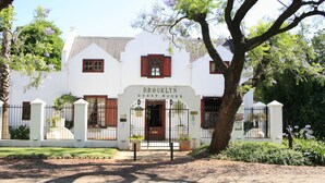 Un edificio blanco con un letrero que dice "Brooklyn Guest House" y una entrada con portón.