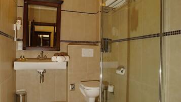 Un baño moderno con cabina de ducha de vidrio, lavabo con espejo y un inodoro.