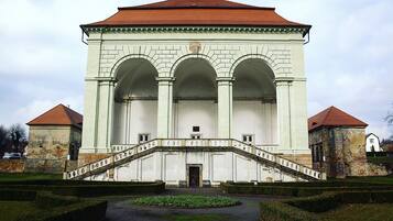 A large, white building with a central arched entrance and a staircase leading up to it.