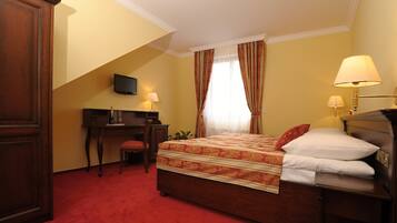 Habitación de hotel con cama, escritorio, silla y televisor montado en la pared.