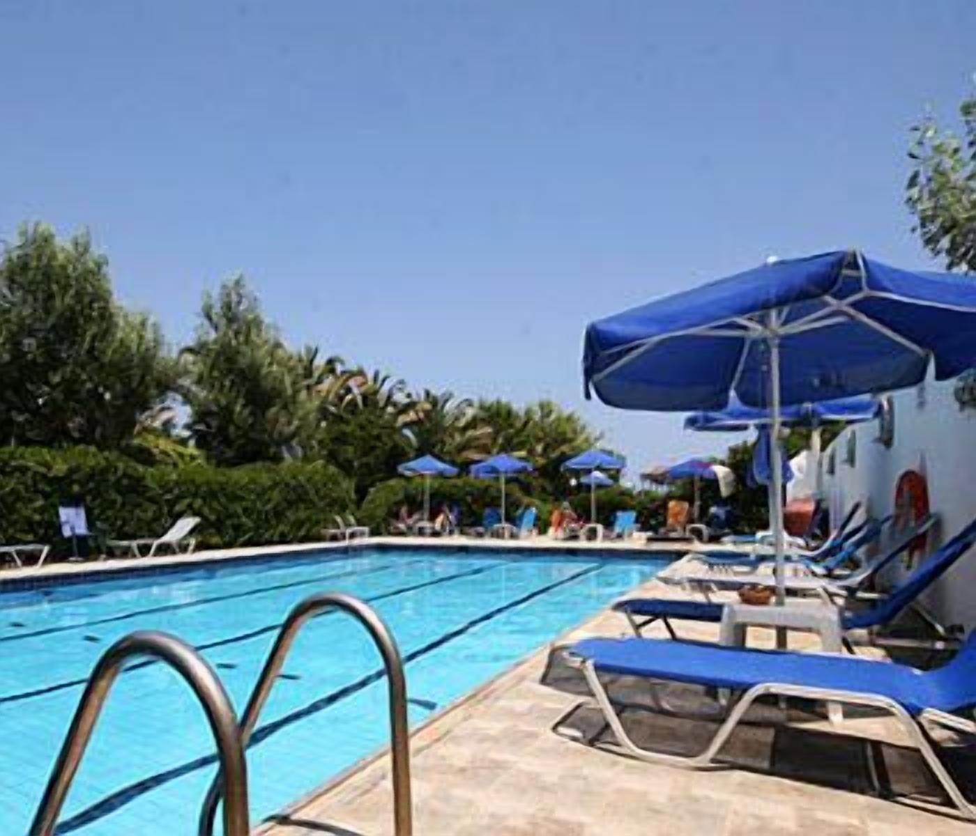 A swimming pool with blue lounge chairs and umbrellas.