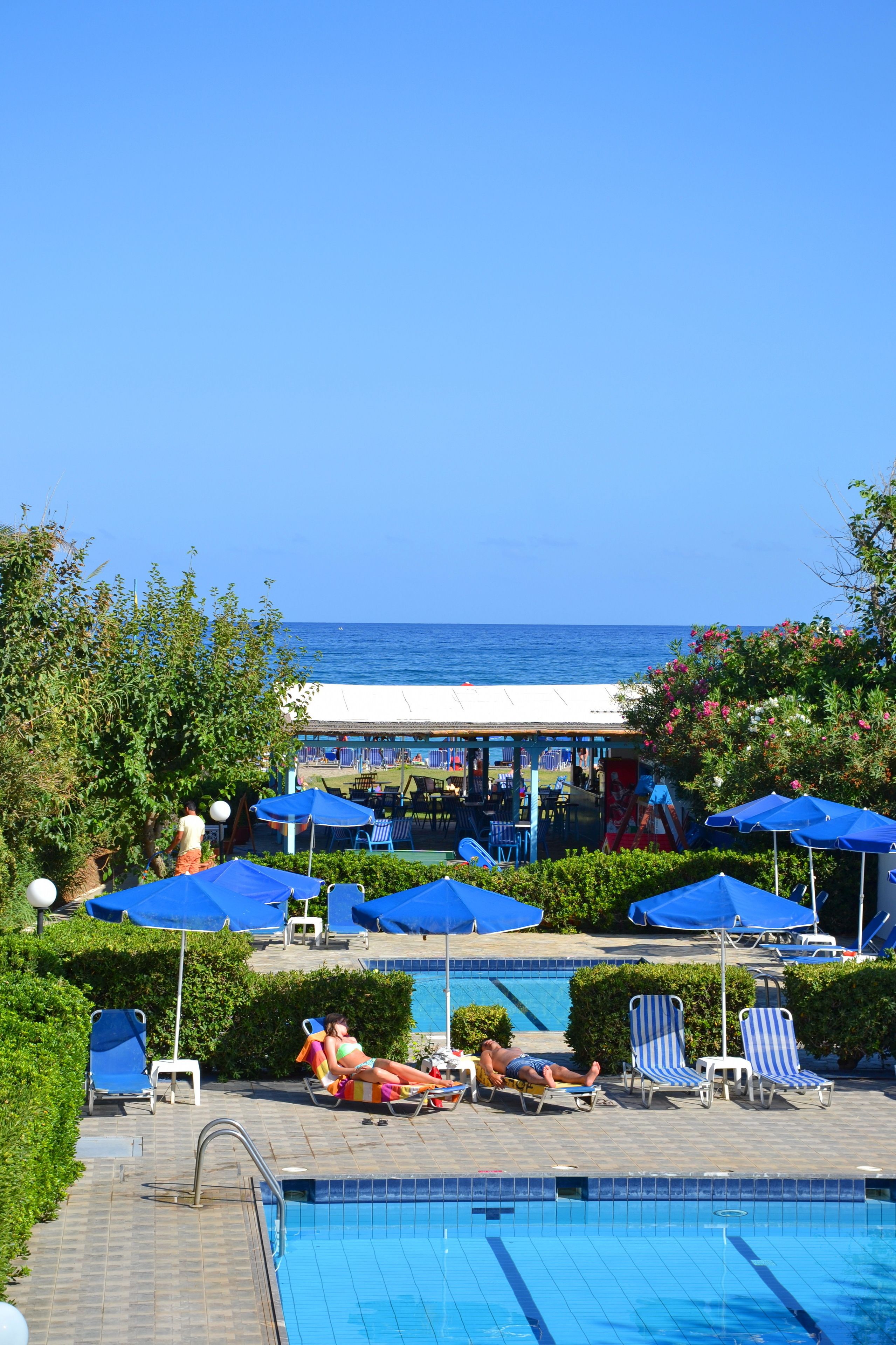 Een zwembadterras met ligbedden en parasols, een zwembad en uitzicht op de oceaan.