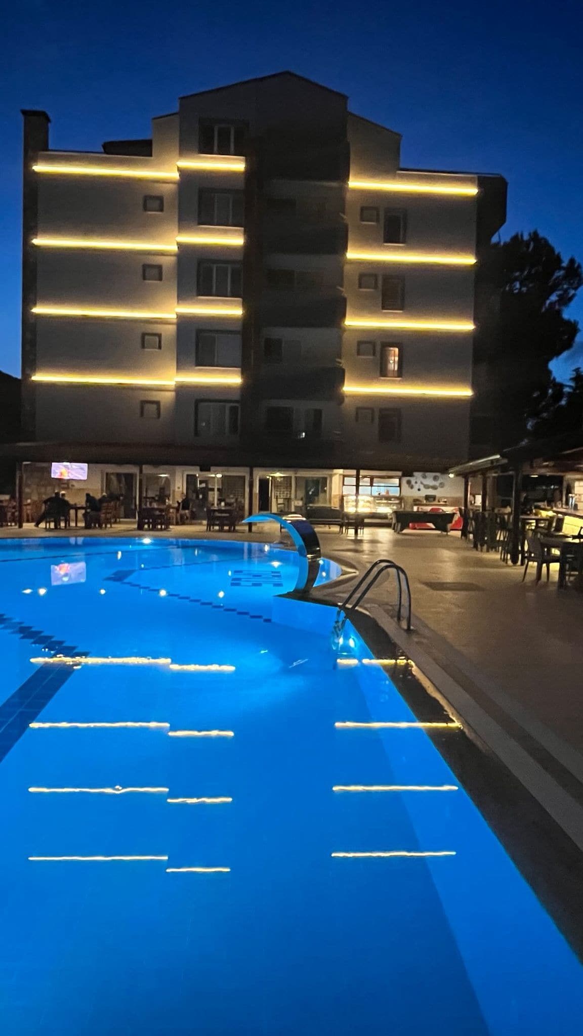 Ein Swimmingpool mit glatter, blauer Wasseroberfläche, umgeben von einem Mehrstöckengebäude mit Balkonen.