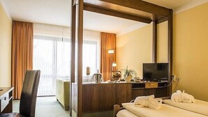 Hotellihuone, jossa on sänky, työpöytä, tuoli, televisio ja suuri peili.
