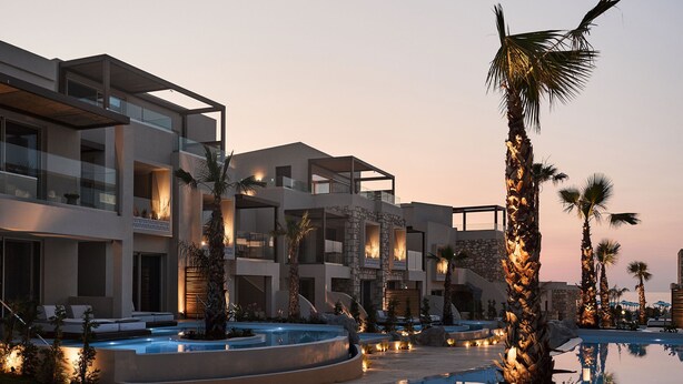 A modern hotel with a swimming pool, palm trees, and a sunset sky. - Uzenie All Suites Boutique Resort - Adults Only (Rethymno)