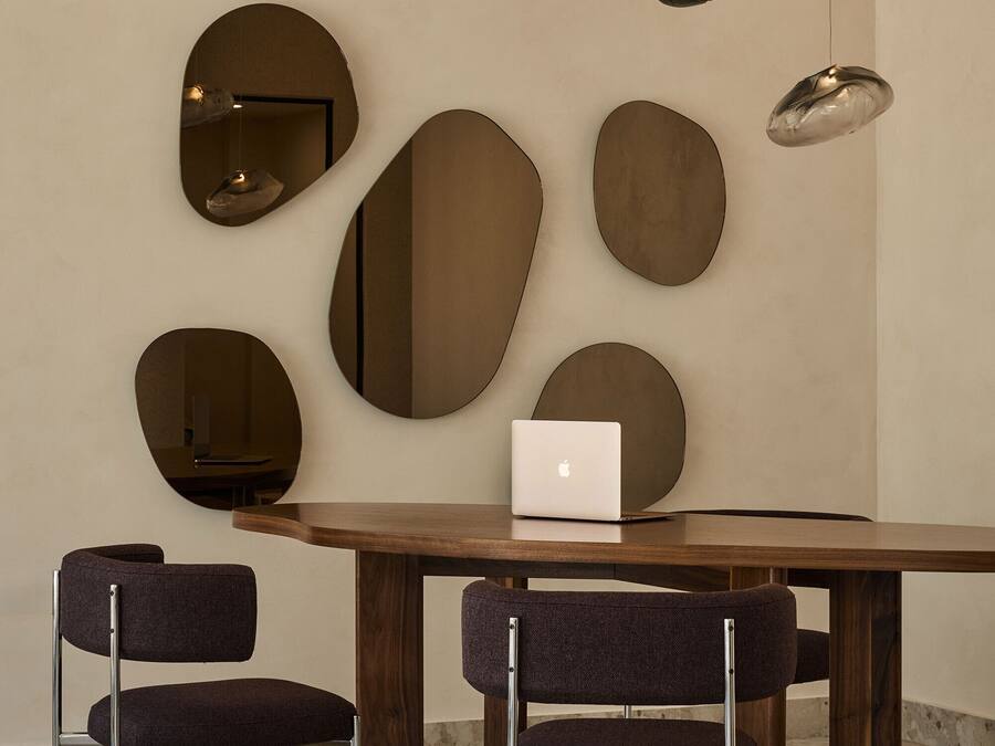 Un comedor moderno con una mesa de madera, dos sillas tapizadas y un ordenador portátil sobre la mesa.