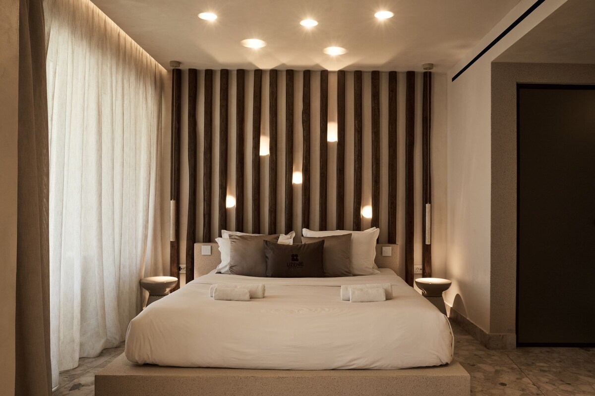 Un dormitorio moderno con una cama grande, mesitas de noche y una pared con listones de madera verticales.