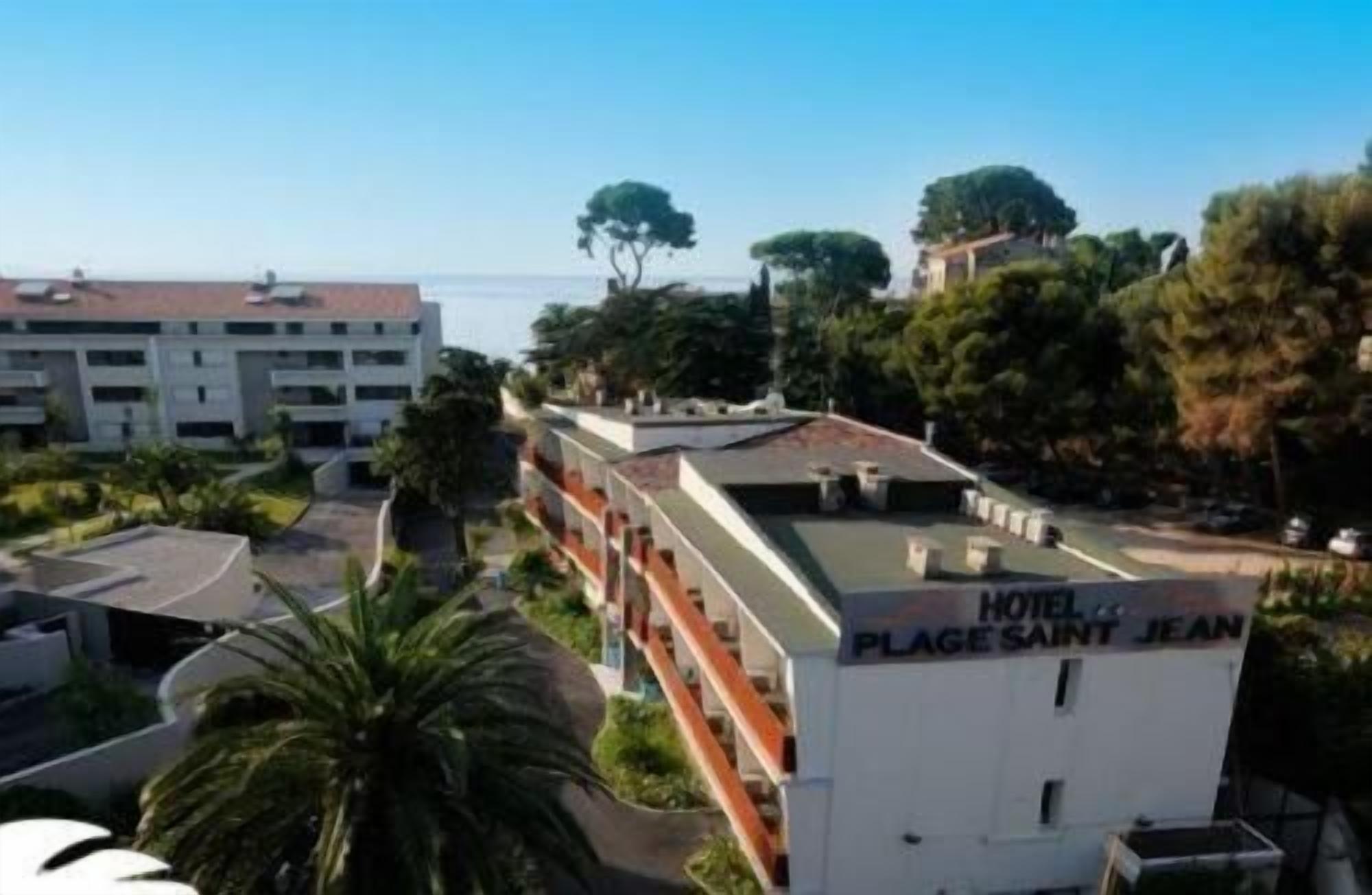 A hotel named "Place Saint Jean" with a rooftop terrace, surrounded by greenery and a view of the sea.
