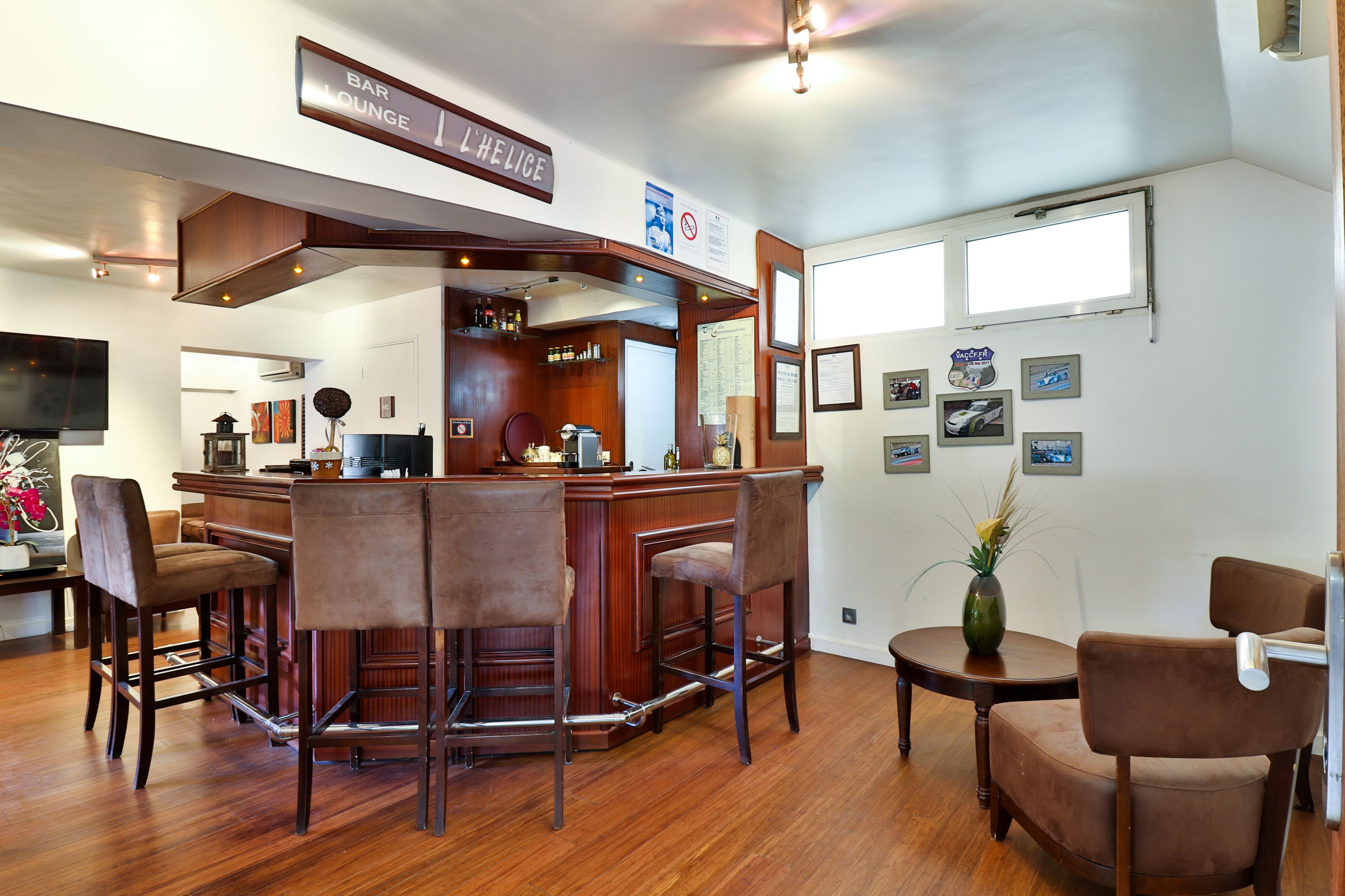 Un área de bar o sala de estar con taburetes de madera, una barra y un televisor montado en la pared.