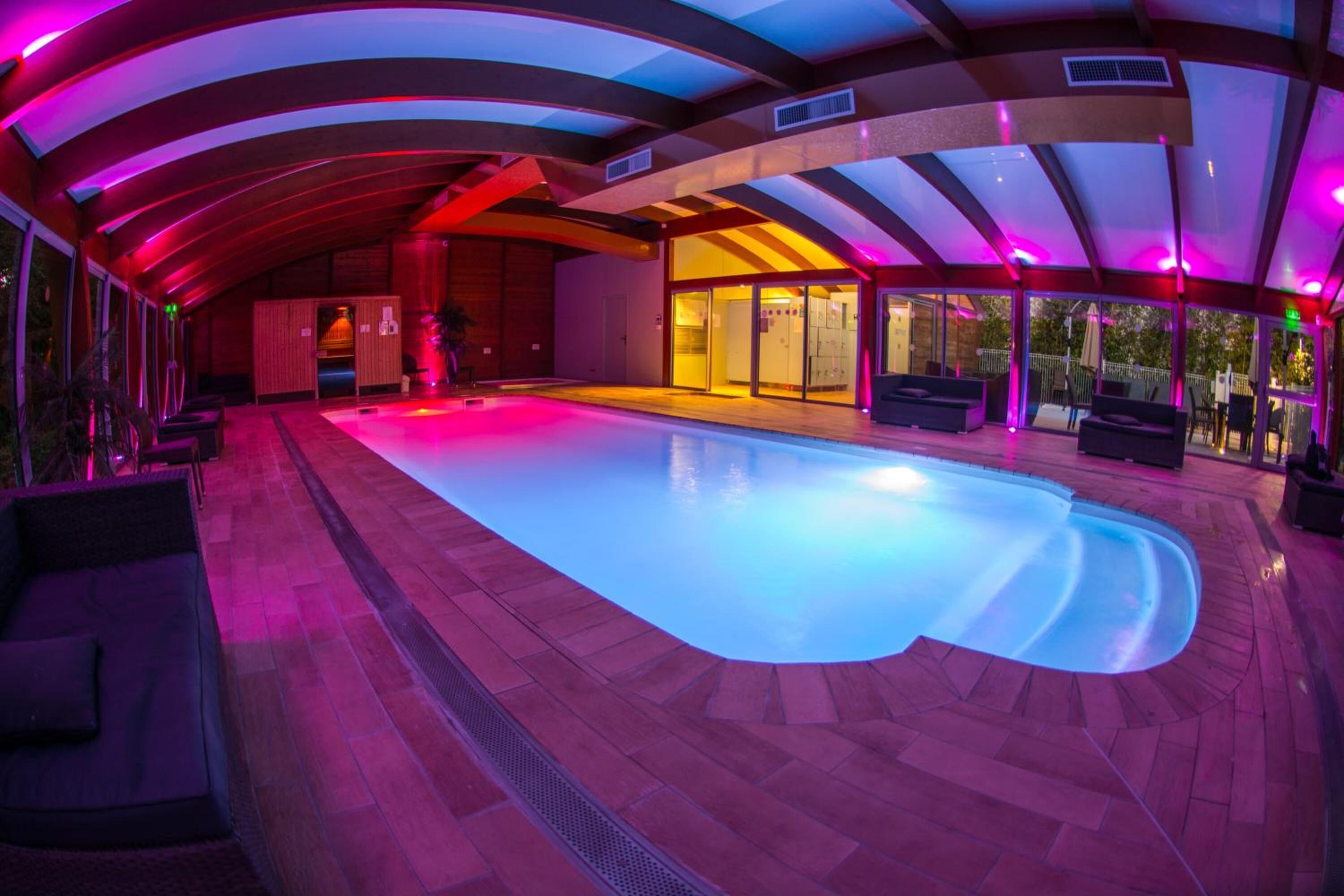 A swimming pool with a curved edge, surrounded by wooden flooring and seating areas.
