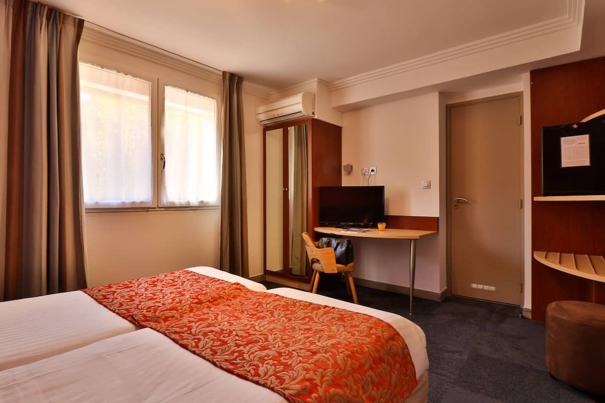 Une chambre d’hôtel avec un grand lit, un bureau avec un ordinateur, une chaise et une armoire.