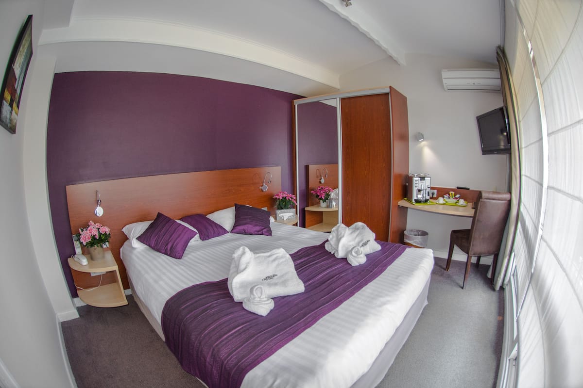 Une chambre d’hôtel avec un grand lit, un bureau, une chaise et un téléviseur.