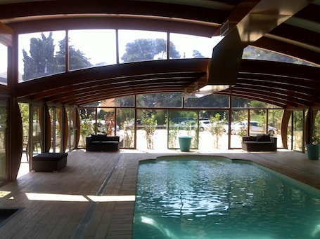 Una piscina techada, sillones reclinables de piscina