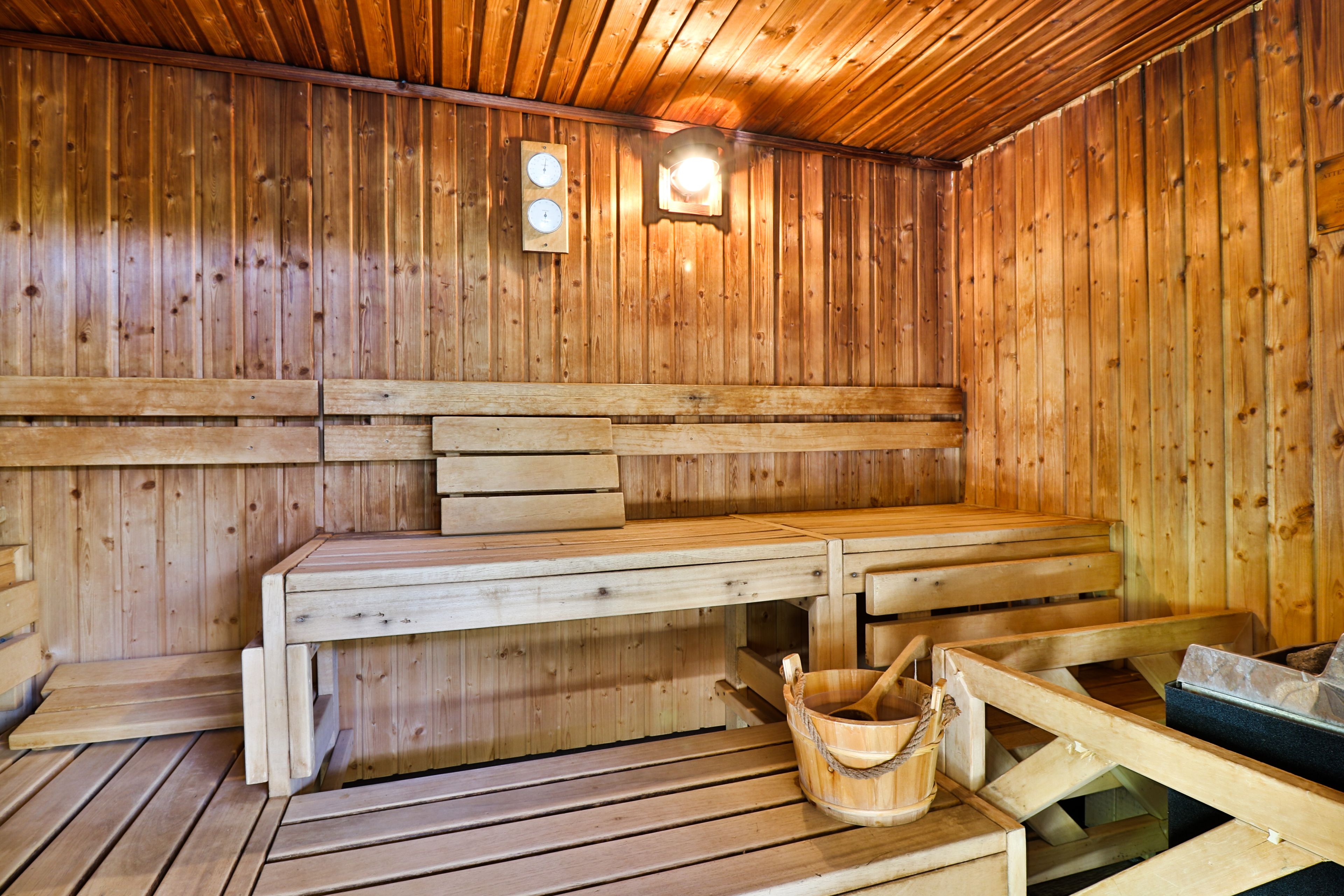 A wooden sauna with benches and a bucket.
