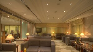 A hotel lobby with a checkered floor, multiple seating areas, a television, and a reception desk. - Siji Hotel Apartment (Al-Fujairah)