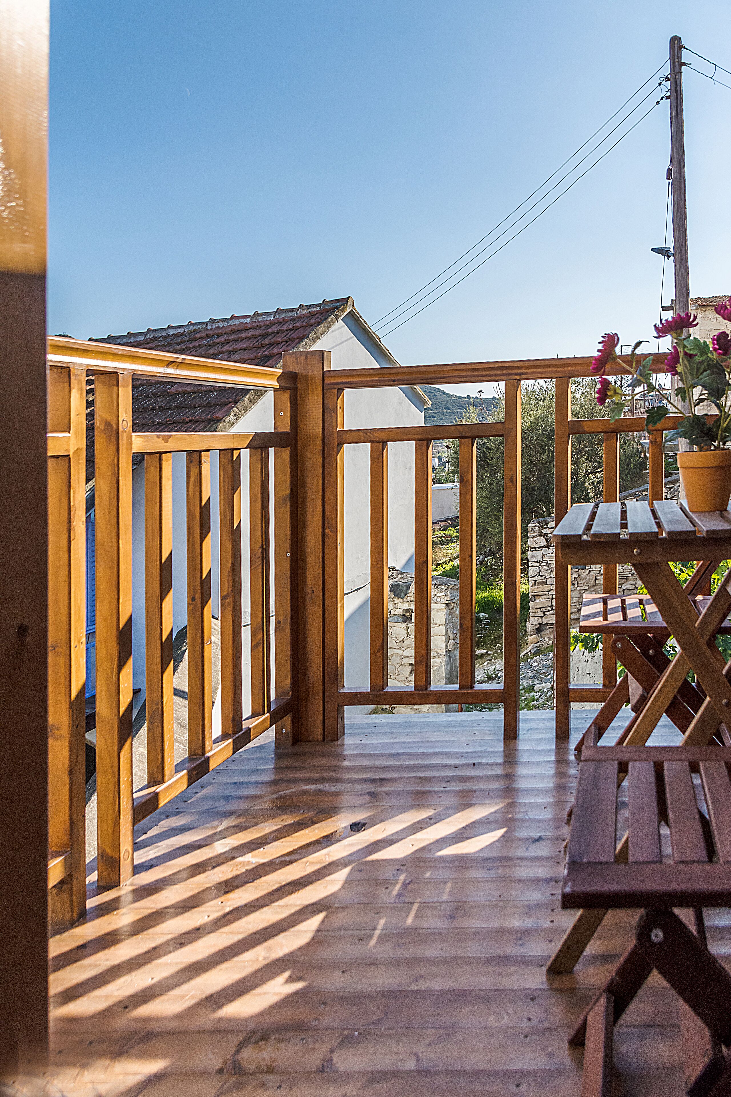 A wooden deck with a wooden railing, a picnic table, and a potted plant.