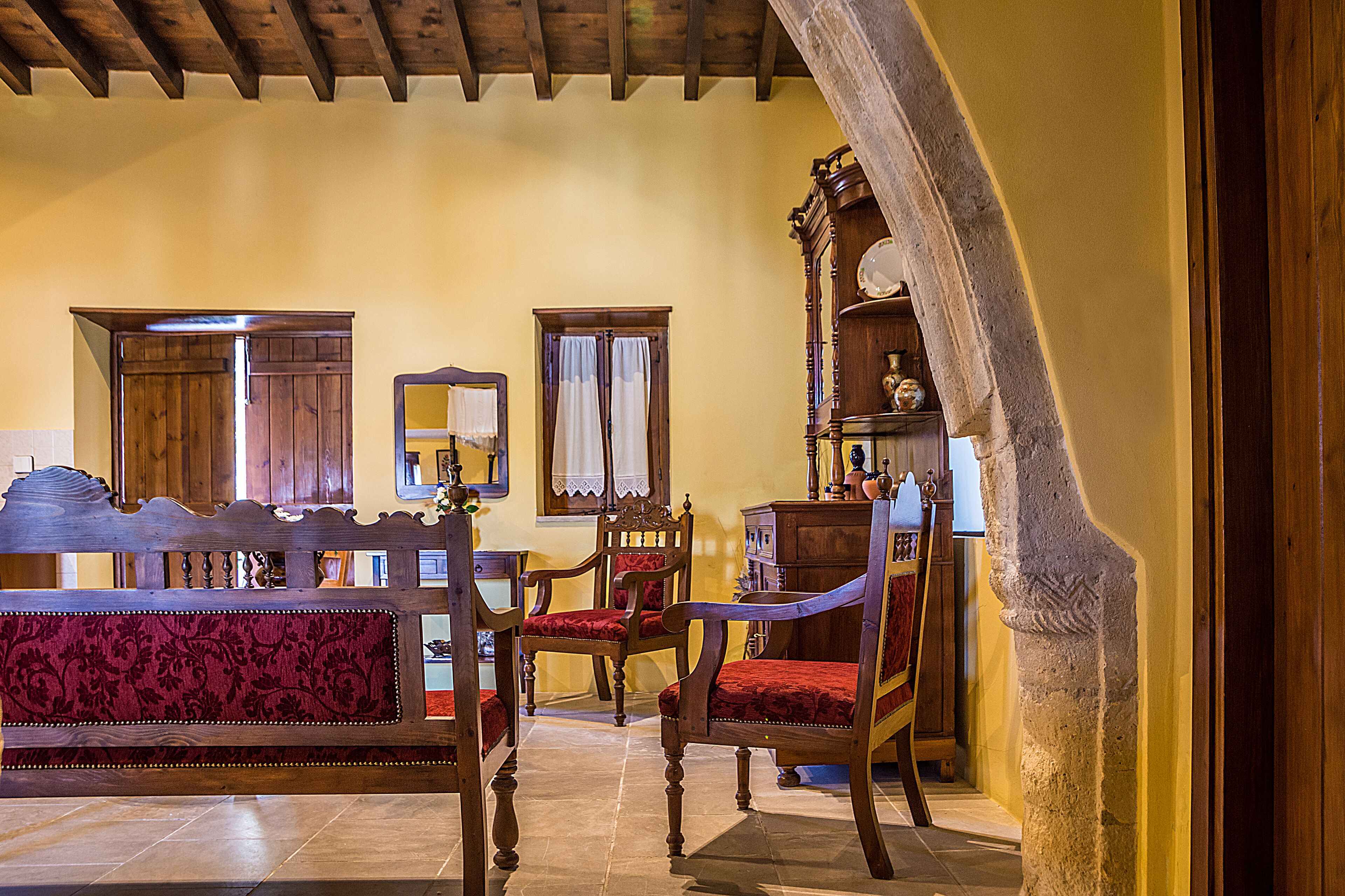 A room with a wooden bench, a red upholstered chair, and a wooden cabinet with a clock.