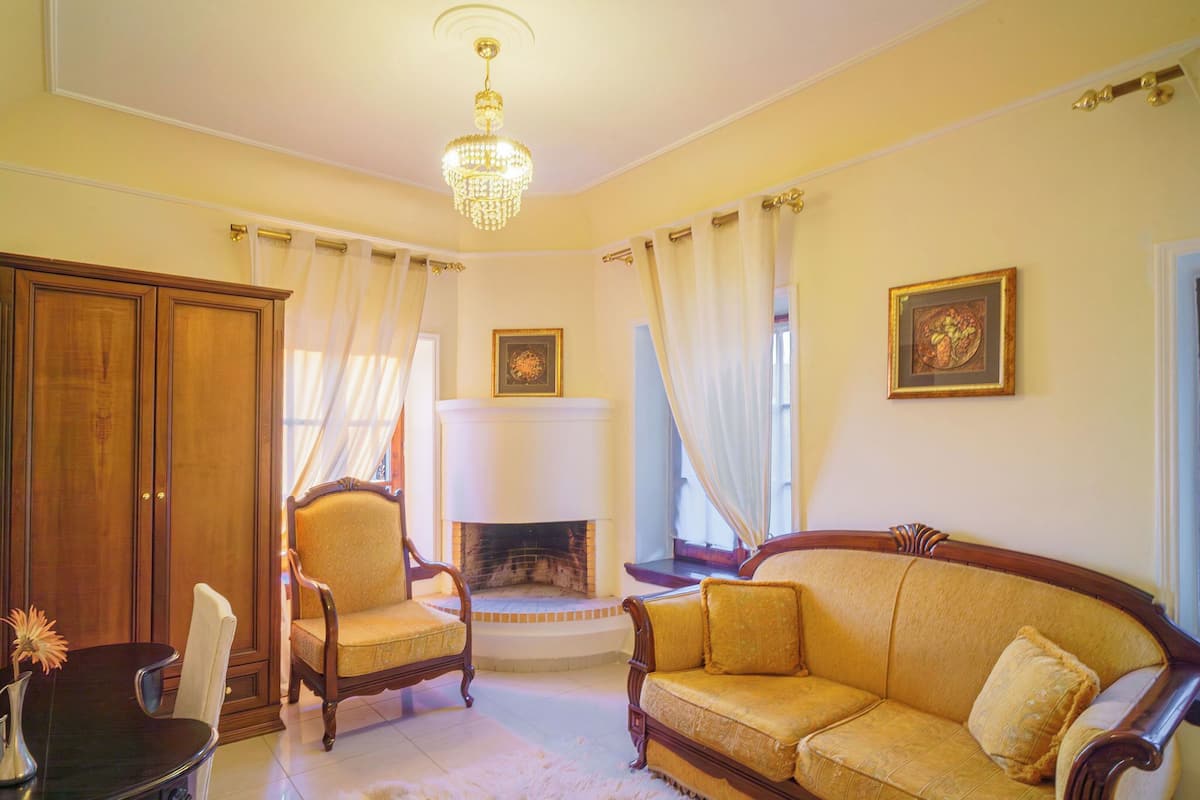 A room with a fireplace, a sofa, a chair, and a cabinet.