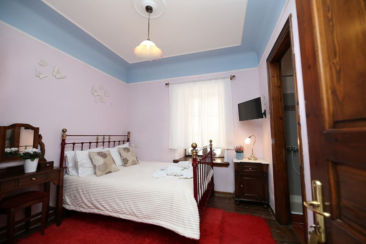 A bedroom with a bed, bedside table, lamp, and a wooden wardrobe.