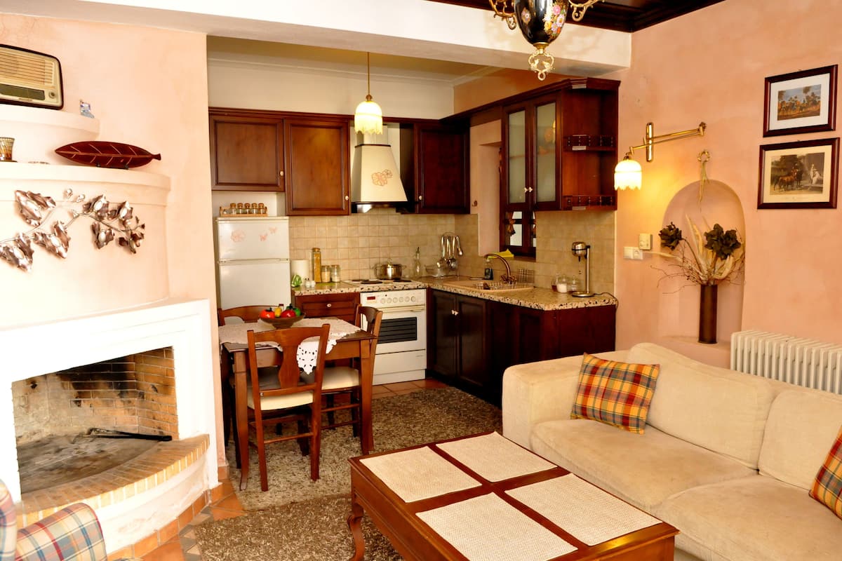 A cozy living room with a fireplace, a sofa, and a dining area with a table and chairs.
