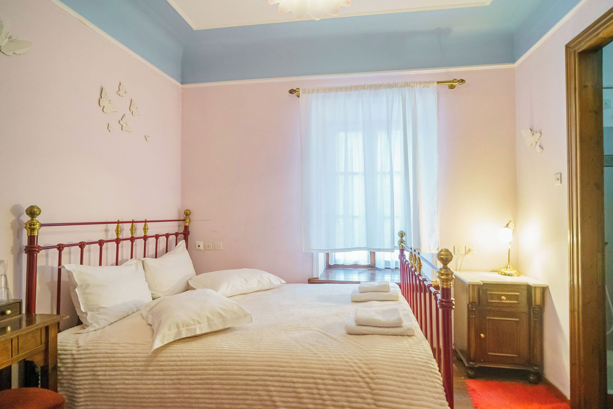 A bedroom with a bed, a nightstand, a dresser, and a window with curtains.